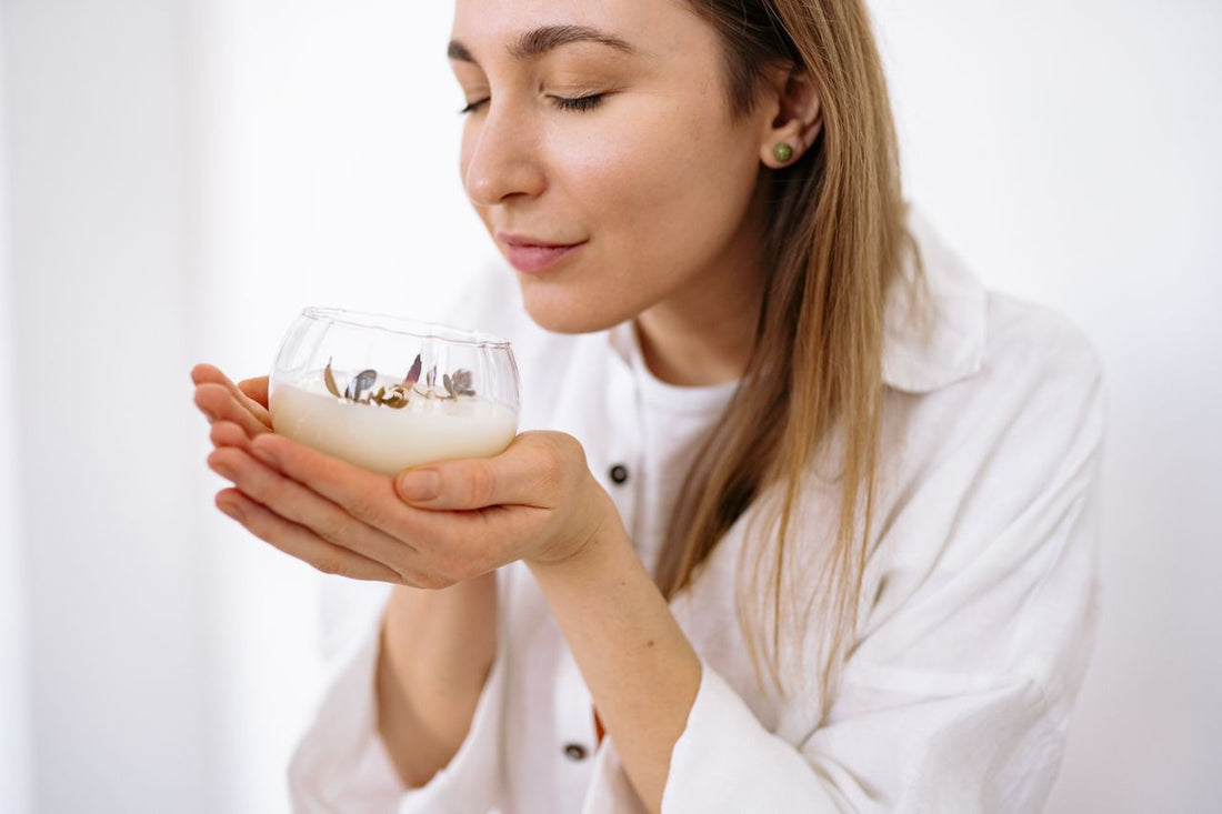A woman enjoying a candle’s fragrance in a glass jar
